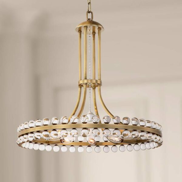 A chandelier hanging from a ceiling in a room. The chandelier is made of brass and has eight cascading crystal drops.