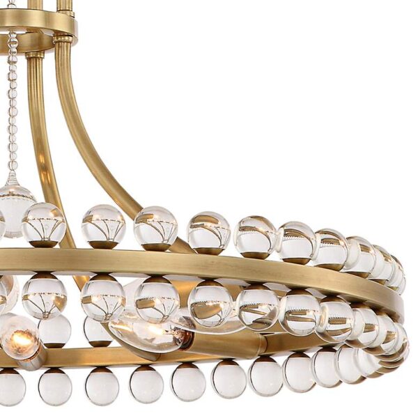 A close-up of a brass chandelier with clear glass beads. The chandelier has four lights and is suspended from a white ceiling.