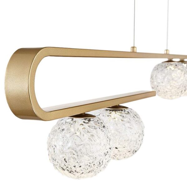 Close-up of a modern pendant light with three clear glass spheres hanging from it. The light fixture is made of brushed gold metal and has a white diffuser.