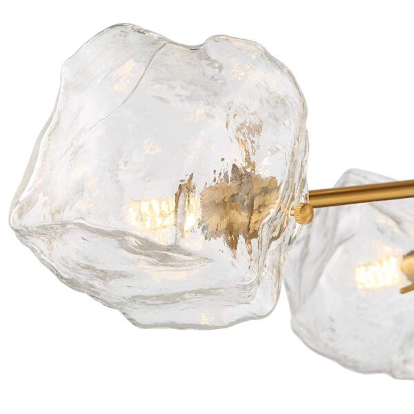 A close-up of a clear glass ice cube pendant light with a gold shade. The light is suspended from a chain and is attached to a ceiling. Title: